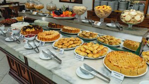 A buffet with various desserts and pastries, including a large cake labeled "EMPADEO DE FRANGO". - Arraial do Sol Beach Hotel (Porto Seguro)