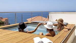 Une terrasse en bois avec un jacuzzi donnant sur la mer.