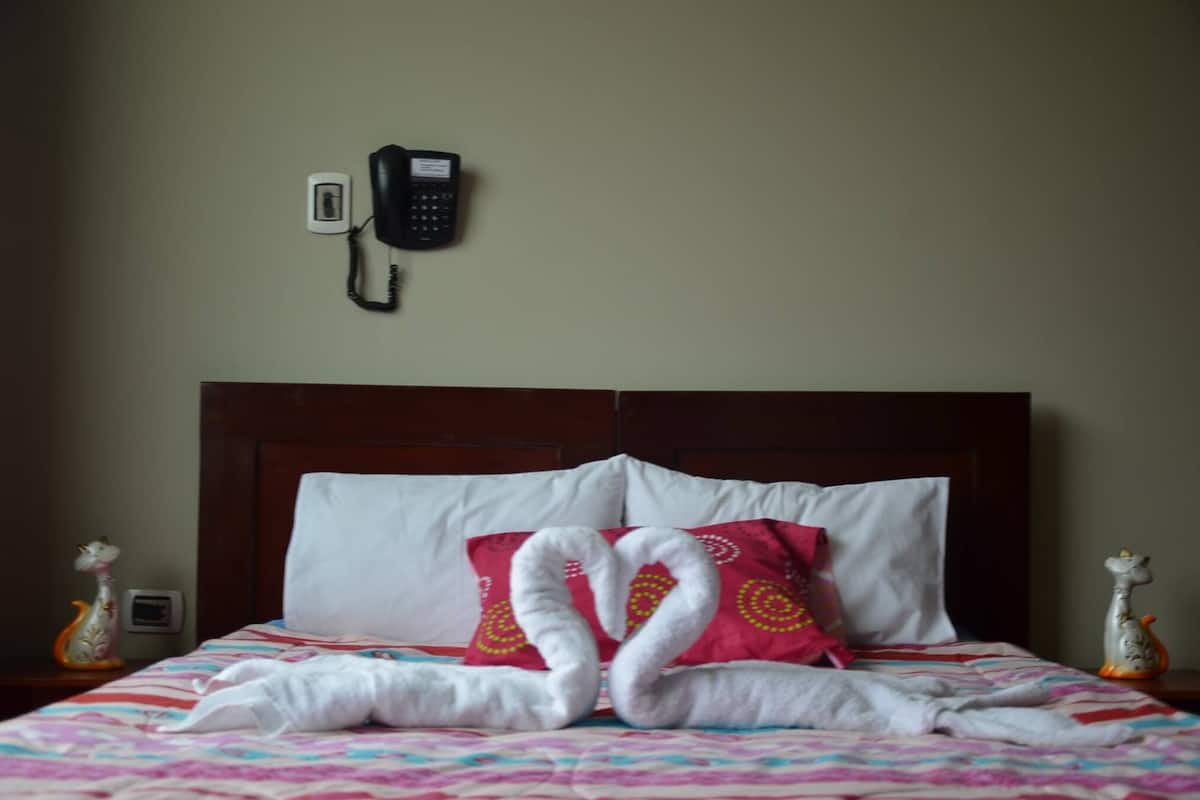 Een hotelkamer met een bed, een telefoon aan de muur en decoratieve objecten op het nachtkastje.