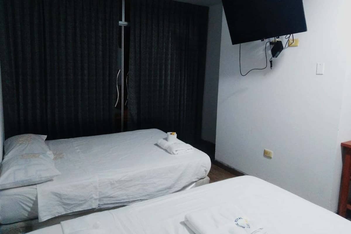 Een hotelkamer met twee bedden, een flatscreen televisie aan de wand en een gordijn voor het raam.