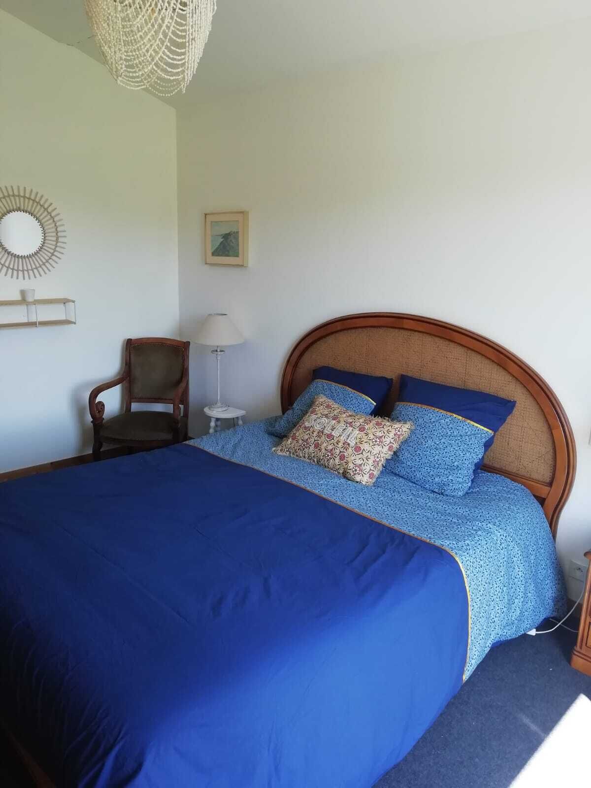 Ein Schlafzimmer mit einem großen Bett, einem Holzkopfstück, einem Sessel, einer Lampe und einer Wanddekoration.