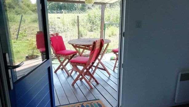 A room with a bed, a sliding glass door leading to an outdoor patio with a table and chairs.