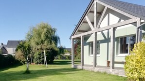 A house with a well-maintained lawn, a swing set, and a large window overlooking the yard.