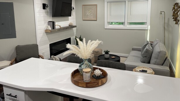 Un salon moderne doté d’une cheminée, d’un téléviseur à écran plat, d’un canapé et d’un coin repas avec une table blanche.