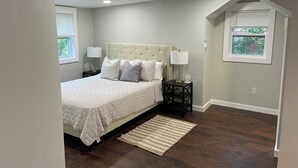 Une chambre à coucher avec un lit, des tables de chevet, un tapis et une fenêtre.