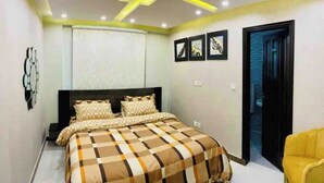 A bedroom with a bed, a headboard, a wall-mounted artwork, and a door. - 102 Luxury apartment to stay! (Lahore)