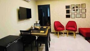 A modern living room with a dining area, a flat-screen TV mounted on the wall, and a ceiling with recessed lighting. - 102 Luxury apartment to stay! (Lahore)