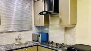 A compact kitchen with a sink, a microwave, and a black refrigerator. - 102 Luxury apartment to stay! (Lahore)