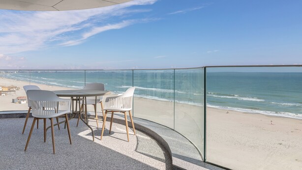 Un balcon doté d’une balustrade en verre donnant sur une plage.