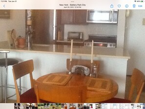 Enjoy cooking and dining in this compact kitchen with a microwave, toaster, and sink, accompanied by a small dining table and two chairs.