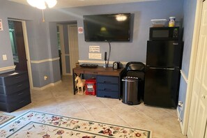 A compact kitchen with a microwave, refrigerator, and a trash bin. - 2 Bedroom Suite (Port Orange)