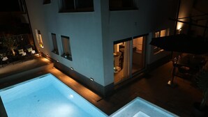 Ein modernes Gebäude mit Pool, Außenbereich zum Sitzen und einer gut beleuchteten Terrasse.