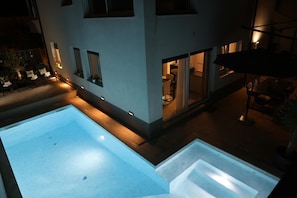 A modern building with a swimming pool, outdoor seating, and a well-lit patio area. - Rooftop Villa w/ Jacuzzi, Swimming pool, Sea Views – Walk to Beach, Sleeps 12 (Okrug Gornji)