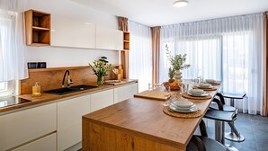 Eine moderne Küche mit Holzarbeitsplatten, einer integrierten Spüle und einem Essbereich mit einem langen Holztisch, gedeckt für sechs Personen.