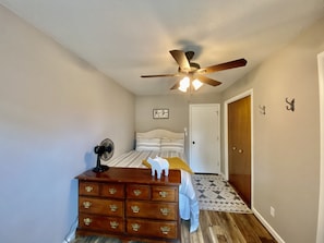 Cozy apartment with a bed, dresser, and table, perfect for a relaxing stay.