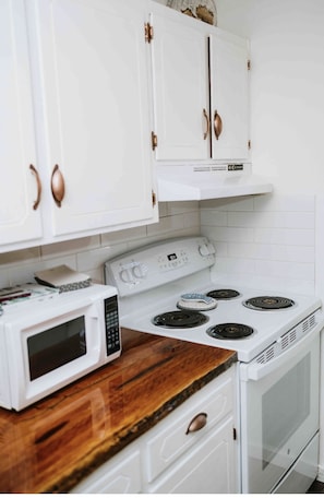 Modern kitchen with classic cabinetry, digital stove, and microwave on the countertop.