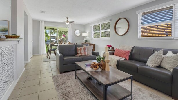 A modern living room with a grey sofa, a wooden coffee table, and a dining area with a table and chairs. - Little Beach House w/ POOLandSPA - Vanderbilt Beach (Naples)