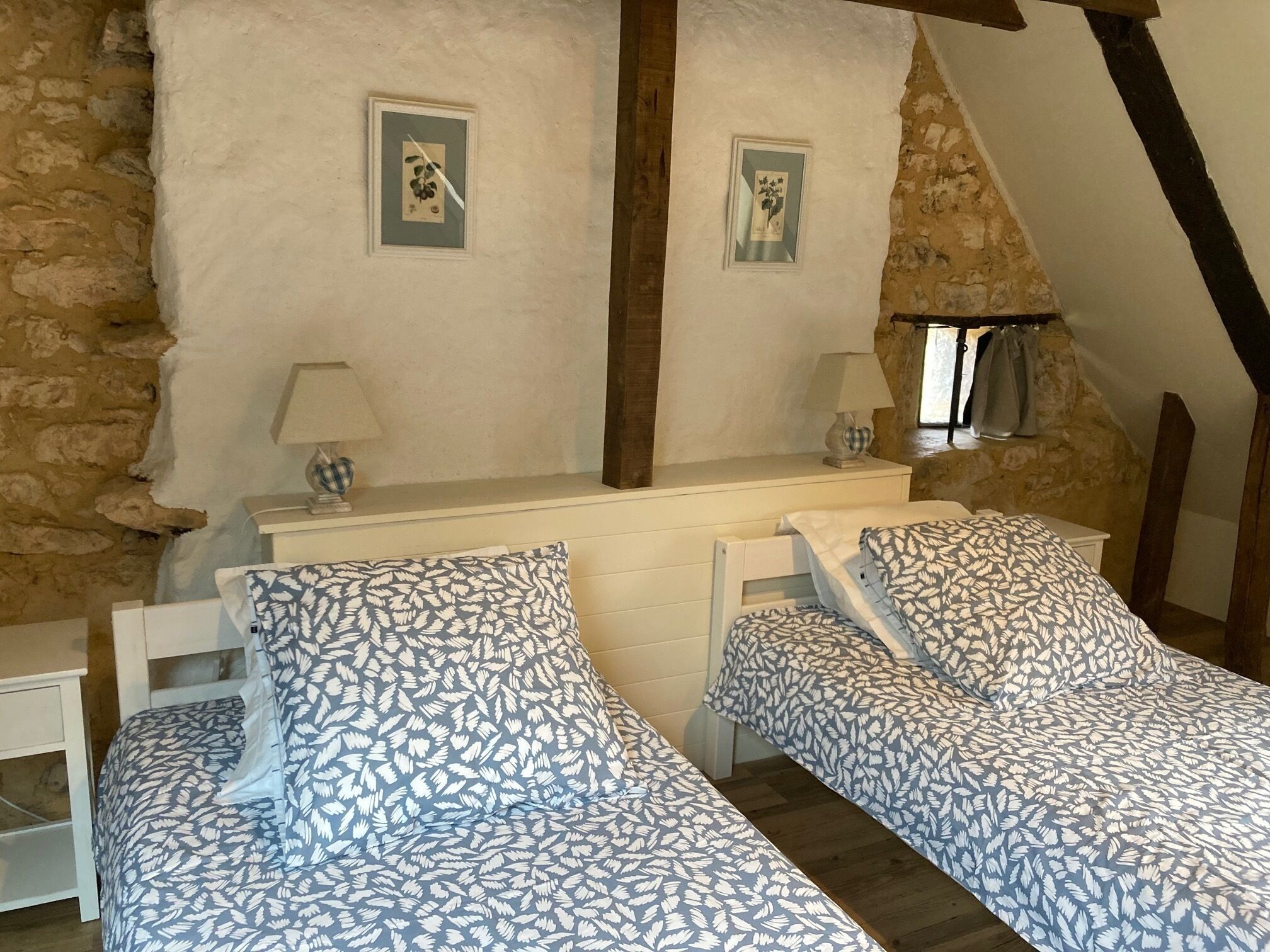 Une chambre confortable avec deux lits simples, une petite table et un mur en pierre.