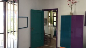 Una stanza con una porta verde acqua, un armadietto viola e una finestra che si affaccia sul verde.