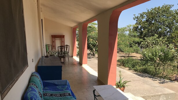 Un'area salotto esterna coperta con divano, sedie e tavolo.