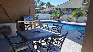 An outdoor patio with a table and chairs, a barbecue grill, and a swimming pool. - We are the coolest hosts on the planet! You will love it here!  (Holiday)
