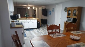 A dining area with a wooden table, chairs, and a decorative mat. A small table with a bowl of food is also visible. - We are the coolest hosts on the planet! You will love it here!  (Holiday)