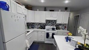 Cozinha moderna com armários brancos, forno embutido e bancada com um vaso e flores.