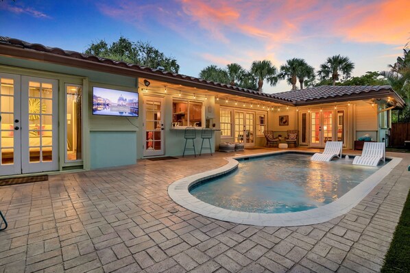 A backyard with a swimming pool, outdoor bar, and seating area. - Sunny Palms Villa - Heated Pool + Hot Tub, 2 miles to the Beach! (Fort Lauderdale)