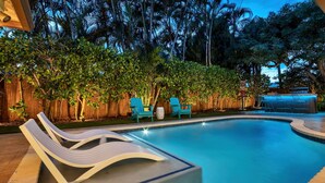 A swimming pool with lounge chairs and a wooden fence. - Sunny Palms Villa - Heated Pool + Hot Tub, 2 miles to the Beach! (Fort Lauderdale)