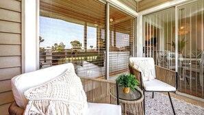 A balcony with wicker furniture, a small table with a plant, and a view of the surrounding area.