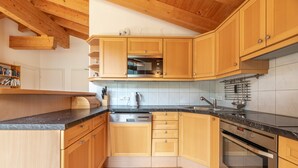A kitchen with wooden cabinets, a black countertop, a built-in oven, and a dishwasher.