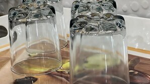 Tre genomskinliga glas på en träbricka, med en vit bakgrund.