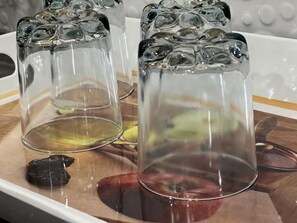 Four elegant tumblers sit on a surface, accompanied by a piece of fruit.