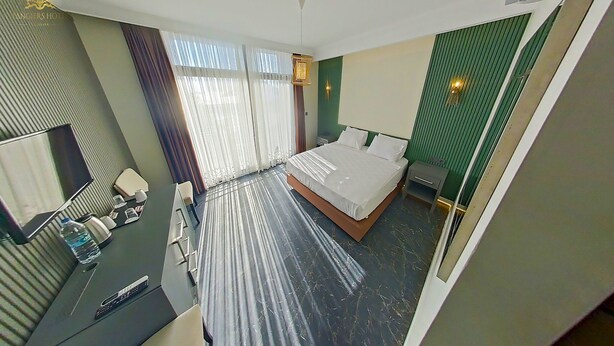 A hotel room with a bed, a desk with a chair, a television, and a window with curtains. - Tangiers Hotel (Bodrum)