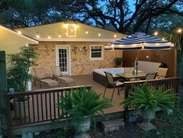 Relax in the serene patio area, complete with a table and chairs, surrounded by lush greenery and a shaded retreat.