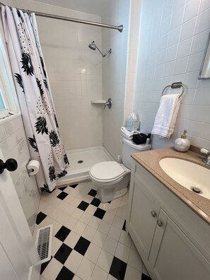 A bathroom with a shower, toilet, sink, and a checkered floor. - Cozy, Bright Beach Retreat In The Woods (Great for Pets & Kids!) (Ocean Pines)