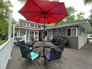 A covered patio with a table and chairs, a red umbrella, and a barbecue grill. - Cozy, Bright Beach Retreat In The Woods (Great for Pets & Kids!) (Ocean Pines)