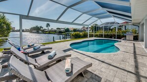 Un espace extérieur abrité avec une piscine, des chaises longues et une vue sur l’eau.