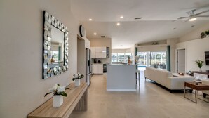 Une cuisine moderne avec un îlot central, un coin repas doté d’un canapé blanc et un grand miroir au mur.
