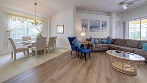 A living room with a dining area, a ceiling fan, and artwork on the walls. - Gorgeous 4 Bedroom, Disney And South Facing Pool (Davenport)