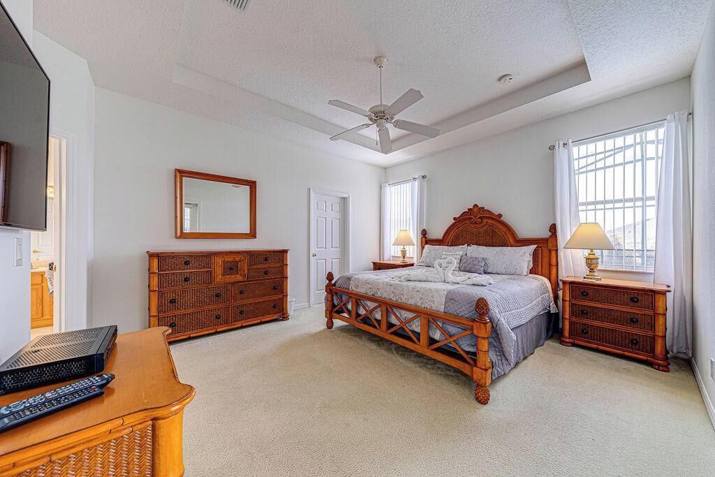 A bedroom with a wooden bed, a ceiling fan, a dresser, a nightstand, and a television.