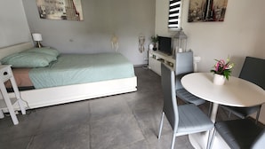 Un dormitorio con cama, mesita de noche, lámpara y un pequeño escritorio con silla.