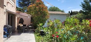 A patio area with outdoor furniture, a covered grill, and a garden with flowering plants. - 2 bedrooms with private bathroom and kitchen in shared villa with  swimming pool (Saint-Raphaël)