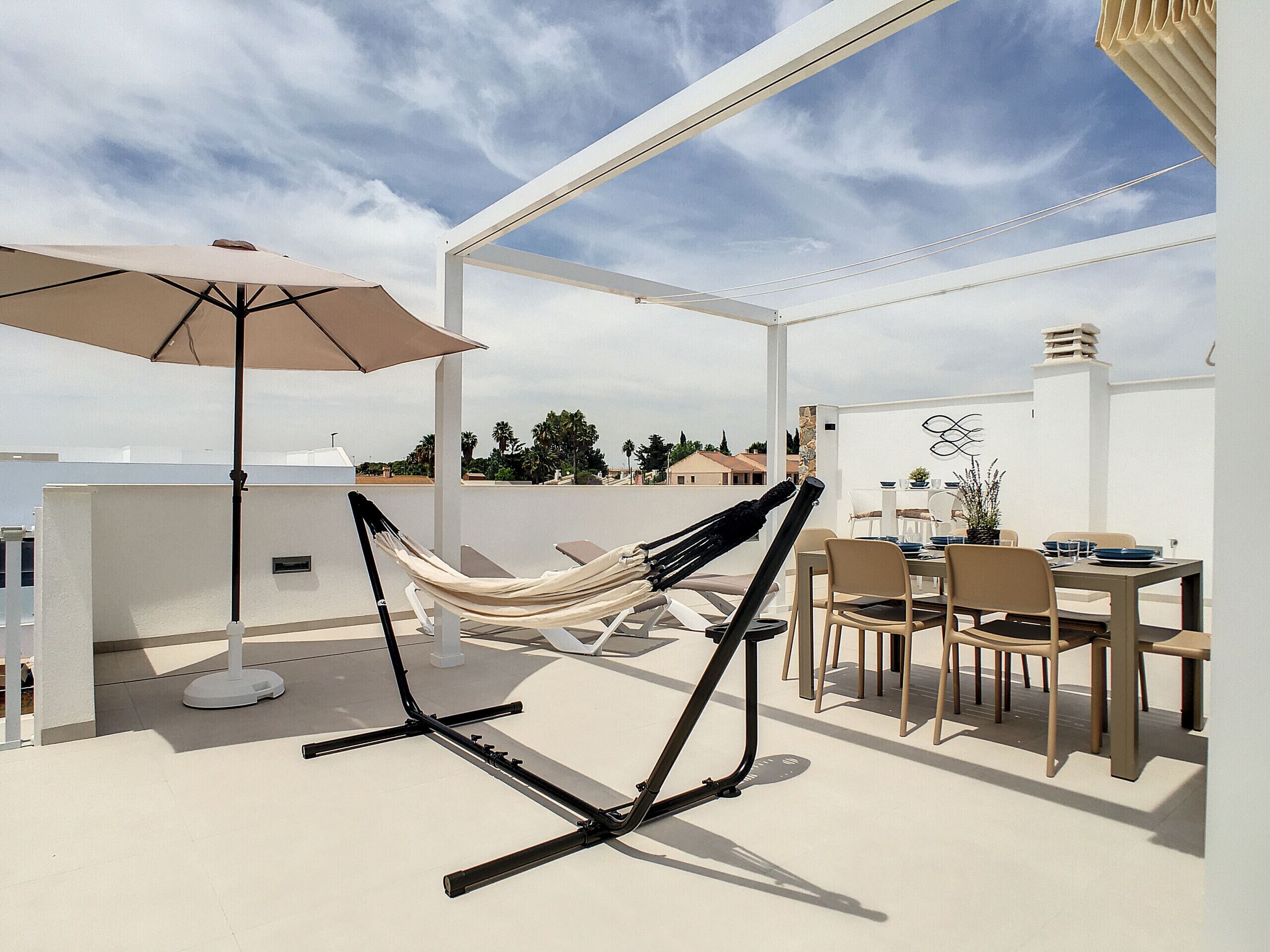 Una terraza en la azotea con una hamaca, mobiliario exterior y una zona de comedor.