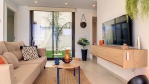 A modern living room with a sofa, coffee table, and a TV mounted on the wall. - Villa with private roof terrace, patio with pool (Santiago de la Ribera)