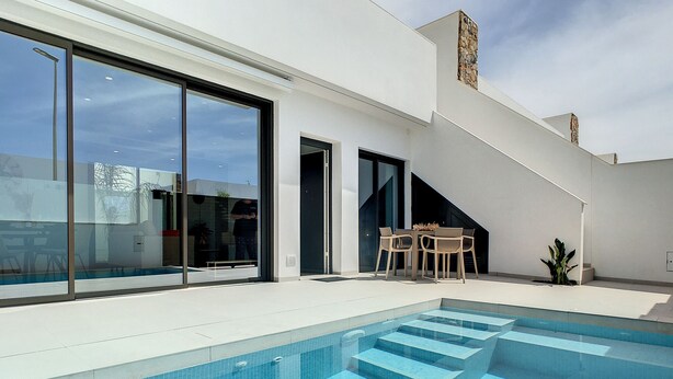 A modern poolside area with a clear blue pool, a set of stairs leading into the pool, and a seating area with a table and chairs. - Villa with private roof terrace, patio with pool (Santiago de la Ribera)