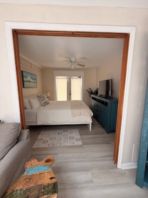 Une chambre à coucher comprenant un lit, un ventilateur de plafond, un téléviseur et un bureau avec des placards.