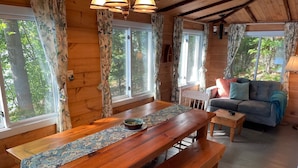 Een houten chalet met een eettafel, banken en een sofa.
