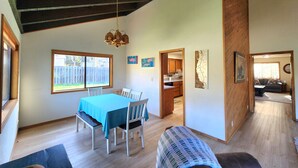 A spacious room with a dining table and chairs, a kitchen area, and a living room with a sofa. - Spacious home with large yard and hot tub- Nearby beach access and dog Friendly! (Brookings)