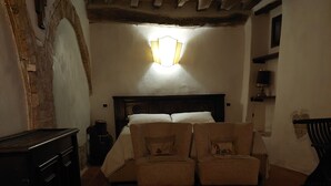 Ein gemütliches Zimmer mit einem Bett, zwei Sesseln, einer Kommode und einer Lampe.